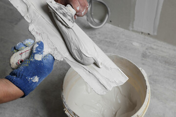 Professional worker putting plaster on putty knife indoors, closeup