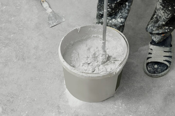 Professional worker mixing plaster in bucket indoors, closeup