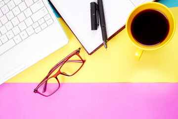 Top view of colorful working table have Headphones,laptop,mobile phone and cup of coffee on color blue,Yellow and pink background for create idea for business or design.Relax time,flat lay.