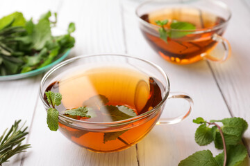 Aromatic herbal tea with mint and rosemary on white wooden table
