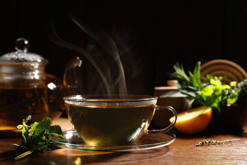 Cup of aromatic herbal tea, mint and rosemary on wooden table