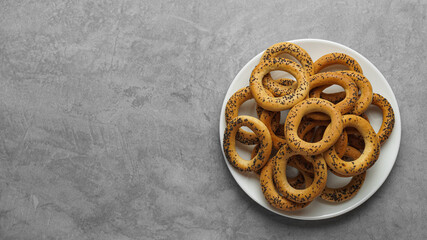Plate with delicious ring shaped Sushki (dry bagels) on light grey table, top view. Space for text