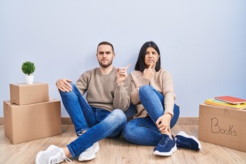 Young couple moving to a new home pointing aside worried and nervous with forefinger, concerned and...