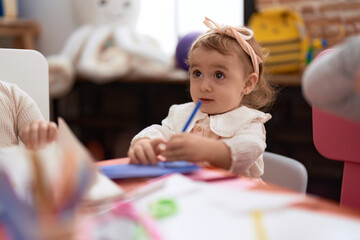 Adorable caucasian girl preschool student drawing on paper standing at kindergarten