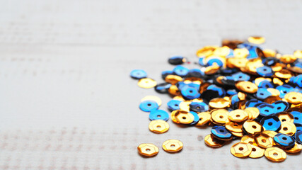 Pile of many yellow and blue sequins on white wooden table, closeup. Space for text