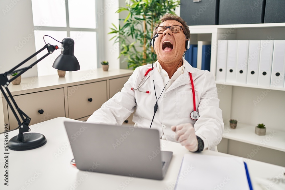 Sticker senior doctor man working on online appointment angry and mad screaming frustrated and furious, shou