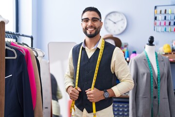 Young arab man tailor smiling confident standing at clothing factory