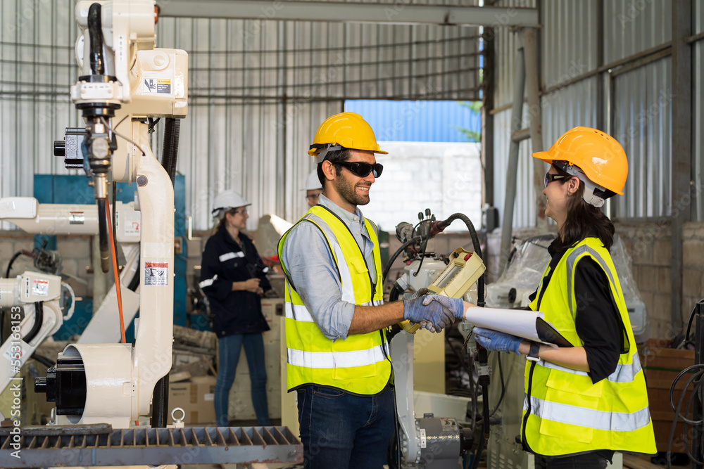 Poster two male and female engineer checking and maintenance robot arm in the workshop. team of technician 