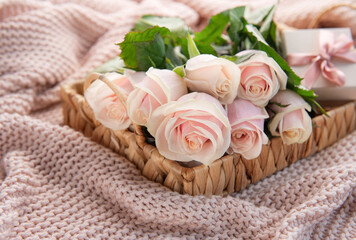 Tray with  bouquet of beautiful pink roses and gift box on  bed.
