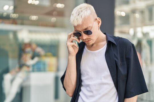 Young caucasian man talking on smartphone with serious expression at street