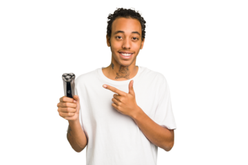 Young African American man holding a razor isolated smiling and pointing aside, showing something at blank space.
