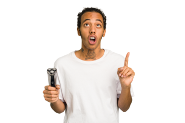 Young African American man holding a razor isolated pointing upside with opened mouth.