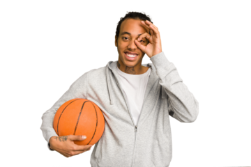Young african american man playing basketball isolated excited keeping ok gesture on eye.