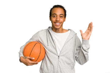 Young african american man playing basketball isolated receiving a pleasant surprise, excited and raising hands.