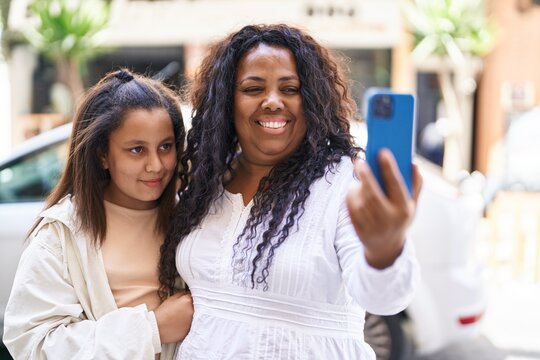 Mother and daughter hugging each other make selfie by smartphone at street