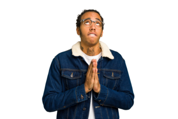 Young African American man isolated holding hands in pray near mouth, feels confident.