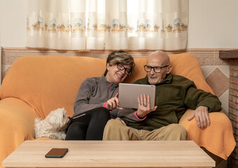 Padre con su hija haciendo videollamada al nieto, persona mayor con su hija sentado en el sillón...