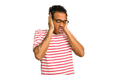 Young African American man isolated covering ears with hands trying not to hear too loud sound.