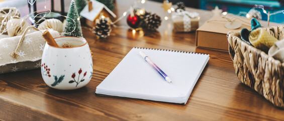 Pen on notepad at home on winter holidays xmas. Goals plans make to do and wish list for new year christmas concept,l writing in notebook. Christmas decoration, gift boxes. 