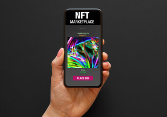 Phone held in hand with sample NFT marketplace website on the screen