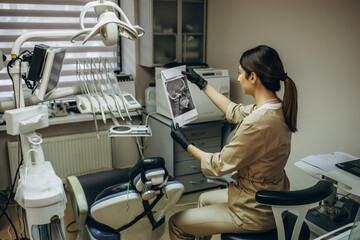 Young female dentist in white coat at workplace. Space for text