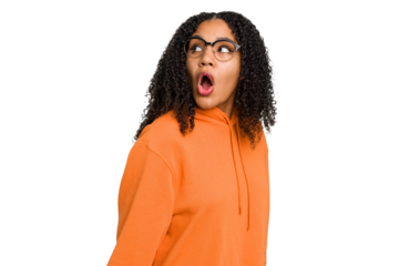 Young african american woman with curly hair cut out isolated looks aside smiling, cheerful and pleasant.