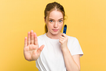 Young cute woman holding a vaper isolated on yellow background standing with outstretched hand...