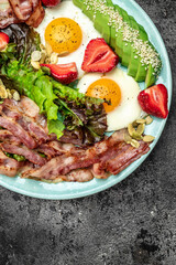 Fried egg bacon with avocado, strawberries and fresh salad, Ketogenic, keto or paleo diet, Delicious balanced food concept. place for text, top view