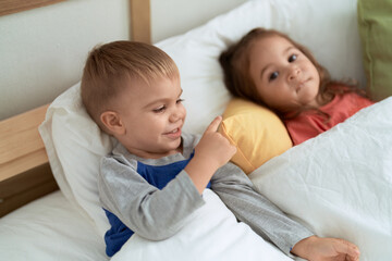 Adorable girl and boy smiling confident lying on bed at bedroom