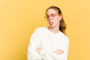 Young caucasian redhead woman isolated on yellow background funny and friendly sticking out tongue.