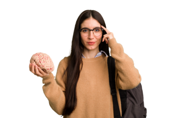 Young caucasian student woman holding a brain isolated pointing temple with finger, thinking, focused on a task.