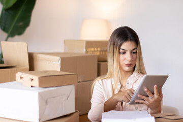 Focused female entrepreneur checking stock inventory in home office. Attractive Caucasian woman...
