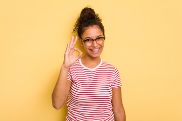 Young Brazilian curly hair cute woman isolated on yellow background cheerful and confident showing...