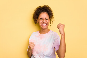 Young Brazilian curly hair cute woman isolated on yellow background cheering carefree and excited. Victory concept.