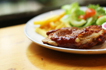 European food, chicken steak with french fries, vegetables and vinegar dressing on a table plate.