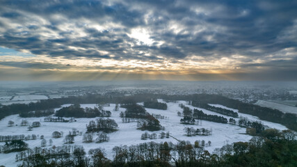 Fototapeta na wymiar Rays of sunshine fall on the snowy hills of The Wirrall in the North of England