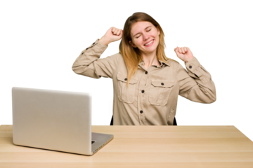 Young caucasian woman in a workplace working with a laptop isolated celebrating a special day, jumps and raise arms with energy.
