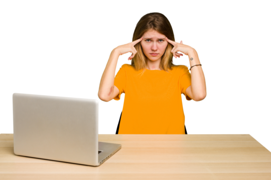 Young caucasian woman in a workplace working with a laptop isolated focused on a task, keeping forefingers pointing head.