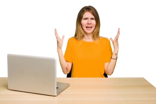 Young caucasian woman in a workplace working with a laptop isolated screaming to the sky, looking up, frustrated.