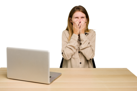 Young caucasian woman in a workplace working with a laptop isolated laughing about something, covering mouth with hands. - Powered by Adobe