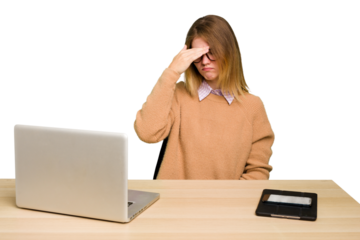 Young caucasian woman in a workplace working with a laptop isolated having a head ache, touching front of the face.