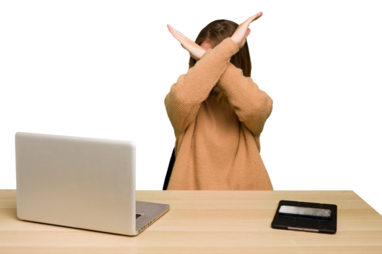 Young caucasian woman in a workplace working with a laptop isolated keeping two arms crossed, denial concept.