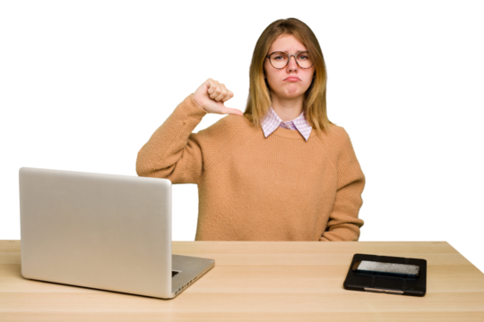 Young caucasian woman in a workplace working with a laptop isolated showing thumb down, disappointment concept.