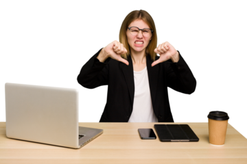 Young business caucasian woman working on her workplace cutout isolated showing thumb down and expressing dislike.