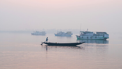 Obraz premium Sundarbans area, West Bengal/India – February 12 2012: Boats in a foggy lagoon at sunrise.