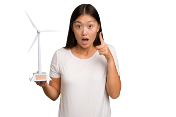 Young asian woman holding a small wind energy mill isolated having an idea, inspiration concept.
