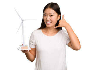 Young asian woman holding a small wind energy mill isolated showing a mobile phone call gesture...
