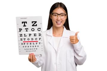 Young asian oculist woman holding a eye chart paper isolated smiling and raising thumb up