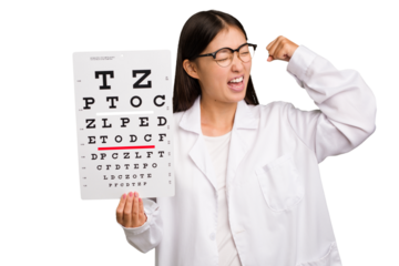 Young asian oculist woman holding a eye chart paper isolated raising fist after a victory, winner concept.