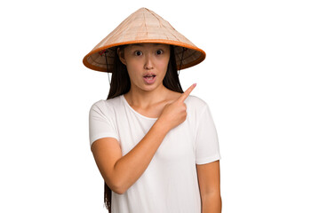 Young asian woman wearing a Vietnamese hat isolated pointing to the side